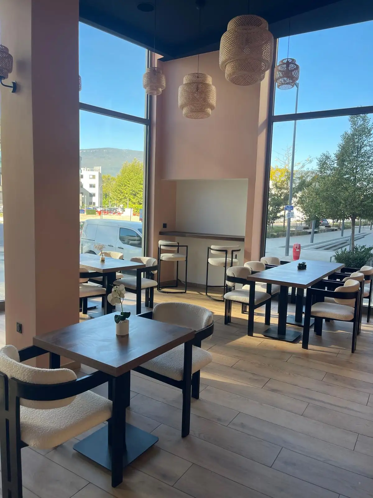 La salle de GreenMood : tables en bois, suspensions en rotin, grandes baies vitrées et la montagne au fond.